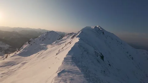 FPV drone flies up snowy alpine ridge at dawn Stock Footage 324519404