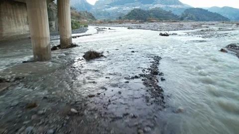An FPV drone flies under a bridge over a mountain river. Stock Footage 329797373