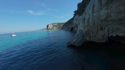 FPV drone flight low over turquoise water along Cala Luna's limestone cliffs Stock Footage 341328083