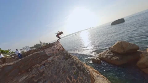 Fpv drone flight man jumps off a cliff into the sea Stock Footage 222776652