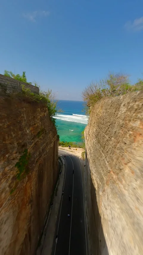 FPV drone flight over road between cliffs and sea at Batu Barak Beach, Bali Stock Footage 306515802