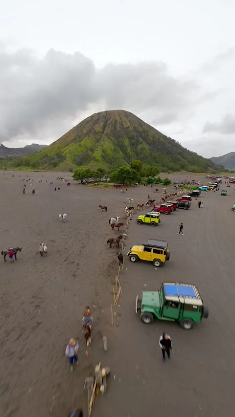 FPV drone flight over Sea of Sand at Mount Bromo with cars, horses, and visitors Stock Footage 322997822