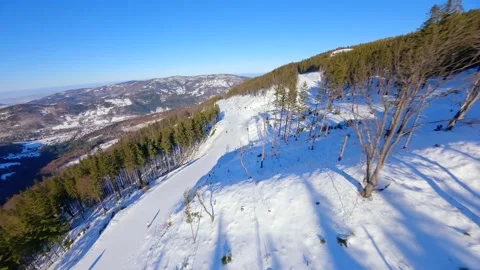 FPV drone flight over snowy ski slope with skiers and mountain view on sunny day Stock Footage 345192773