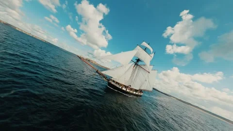 FPV drone flying around two-masted sailing ship cruising on blue ocean under Video stock 330921240