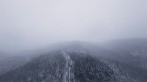 Fpv drone flying between snowy mountain lines in storm Stock Footage 321251633