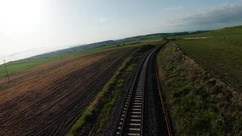 FPV drone flying low along a single railway track cutting through flat plowed Stock Footage 334266755