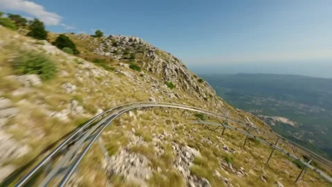FPV drone flying low over rails of alpine coaster Stock Footage 332114539