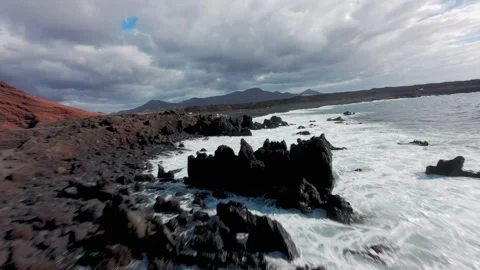 FPV drone flying ober rocky coast and black sand beach in Lanzarote, Spain Stock Footage 331029072