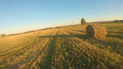 FPV drone flying over a field with bales at sunset in autumn Video stock 160749430