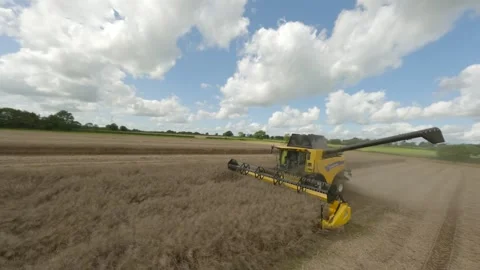 FPV drone gently swoops around tracked combine harvester in rural England Stock Footage 247053137