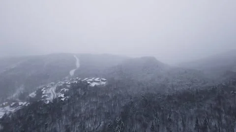 Fpv drone hovering along icy mountain cliff in snowfall Stock Footage 321250501