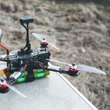 FPV drone lies on the table near the laptop and control panel. Stock Photos