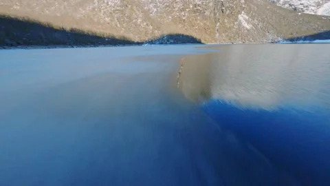 Fpv drone low flyover Bondhusvatnet frozen glacier lake sunny mountains Norway Stock Footage 184503852