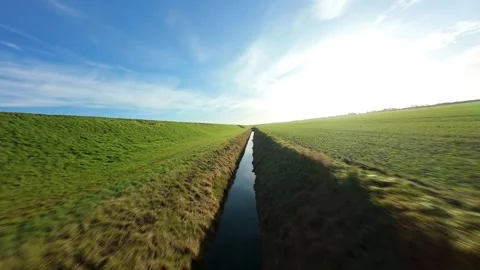 FPV drone low pass over rural landscape and flood banks at sunrise UK 스톡 동영상 324853988