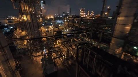 FPV drone night dive into glowing refinery stacks, pipes and smoke billows Stock Footage 321600505