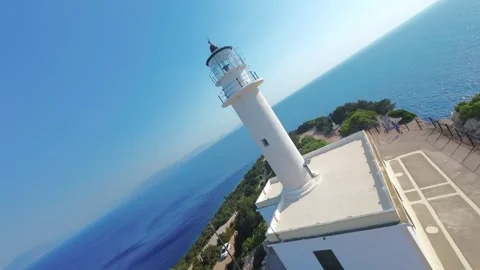 FPV drone orbit around Lefkada Lighthouse above turquoise sea Stock Footage 329667872
