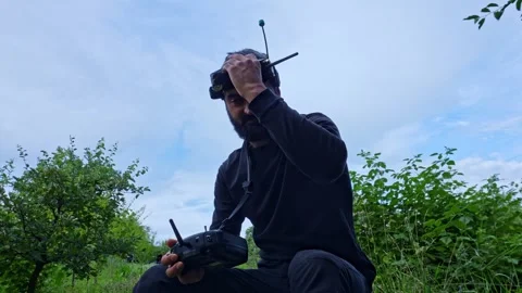FPV drone pilot puts on VR headset glasses siting outdoor blue sky 4K footage Stock-Footage 280365297