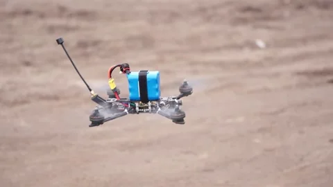 FPV drone resting on dirt ground with battery and frame Stock Footage 334695918