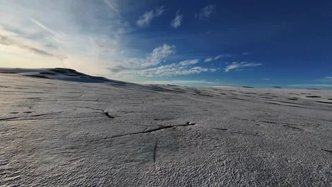 The FPV drone returns over the frozen lake, skimming inches above the ice and Vídeo Stock 328478538
