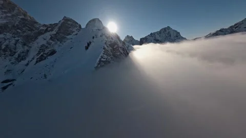 FPV Drone Surfing Clouds Over Fresh Snow Mountain Tops, 4K Stock Footage 323465608