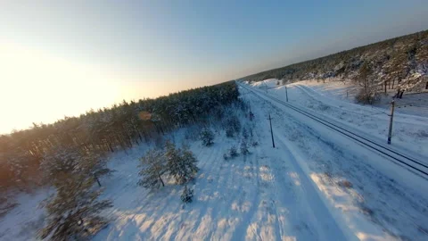 FPV drone view. Fast flight over the railway in the winter forest at sunset 库存影片 147995930