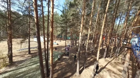 FPV drone view of zipline track with girl in the forest near an obstacle course Stock Footage 220756497