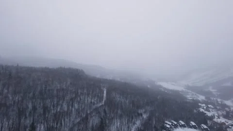 Fpv drone weaving between snowy mountain ridges in storm Stock Footage 321250272