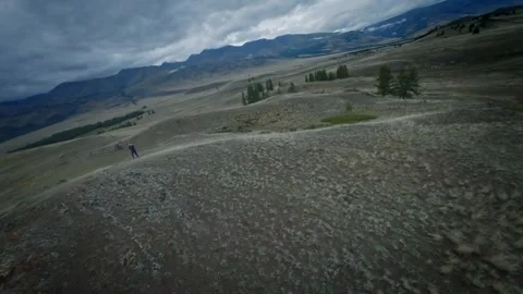 FPV drone will fly low above the ground near a young girl. The girl goes hiking Stock Footage 278368433