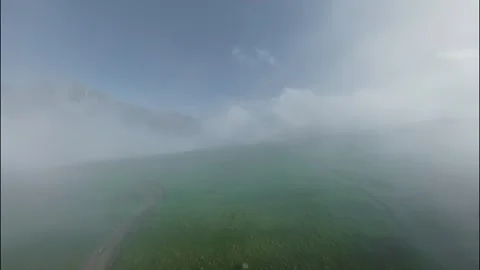 FPV flight through clouds over green landscape with mountains in the distance Stock Footage 341357697