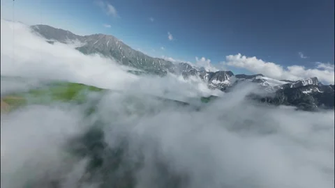 FPV flight through clouds over green mountains and snow-capped peaks Stock Footage 341378424