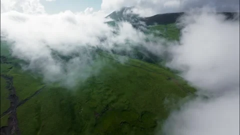 FPV flight through clouds over green hills and mountains in a scenic landscape Stock Footage 341378435