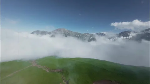 FPV flight through clouds revealing mountains and green landscape below Stock Footage 341378398