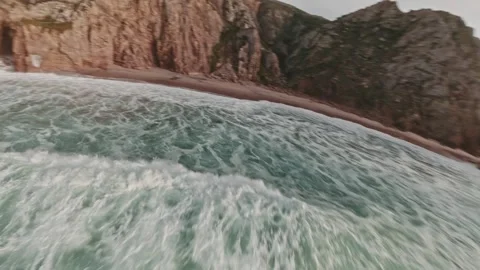 FPV flying fast along rugged coastal cliffside with golden sunset sky over Stock Footage 336201971