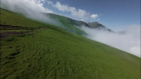FPV low flight over green hillside with clouds rolling across landscape Stock Footage 341358043