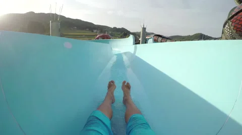 FPV: Man sliding down fun water slide at summer sunset Stock Footage
