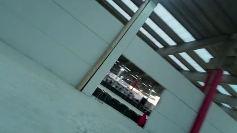Fpv racing drone flying over pilots driving fast go-karts on indoor and Stock Footage 254762794