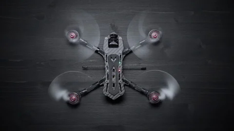FPV Racing Freestyle Drone with Spinning Motors on a Black Wood Workbench Stock Footage