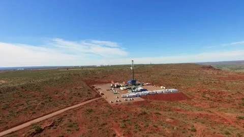 A fracking site in a vast, arid landscape under a clear blue sky, with Video stock 264744958