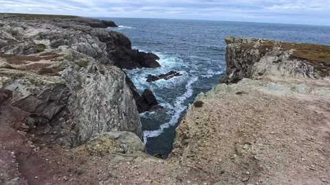 Fractured cliff edge between rocky Welsh Irish sea coastline Видео 337924285