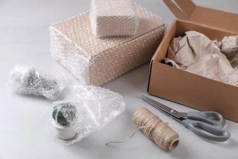 Fragile ceramic decor elements in bubble wrap near cardboard boxes, scissors  Foto stock