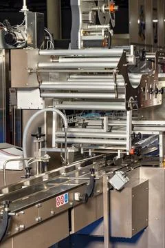 Fragment of an automatic packaging line with roller guides at a food factory. Stock Photos