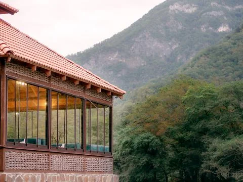A fragment of a cafe with large windows standing in a green mountain valley on a Stock Photos