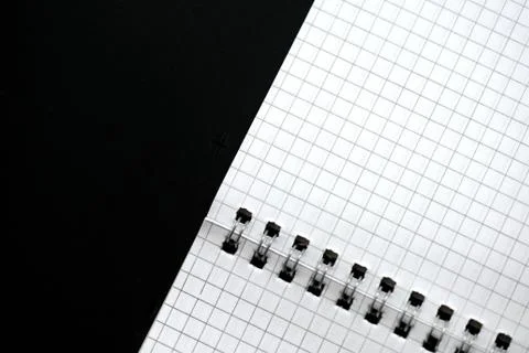Fragment of a checkered notebook on a black background close-up. Top view Stock Photos