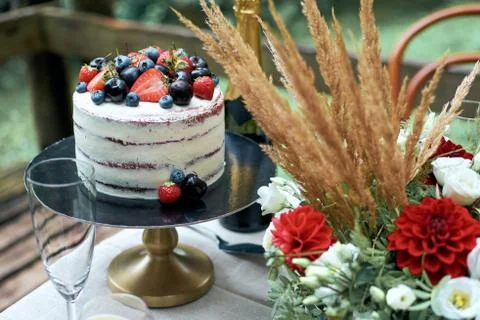 A fragment of a festive table for a romantic dinner. Naked cake decorated wit Stock Photos