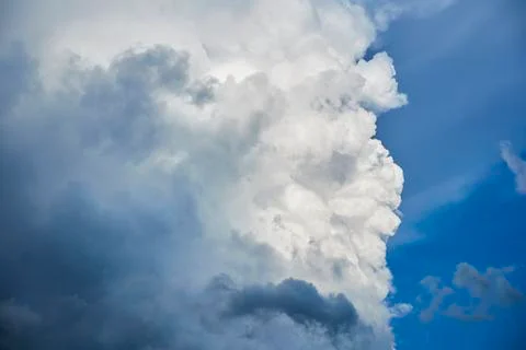A fragment of a large dark cloud, a white cloud against a blue sky Stock Photos