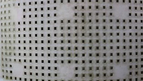 A fragment of a light plastic grille with through square holes. Stock Photos