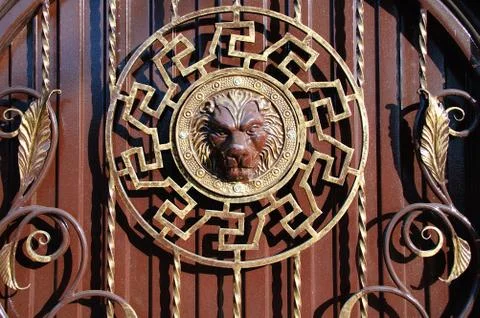 Fragment of a metal gate with elements of forged decor. The head of a lion. Foto stock