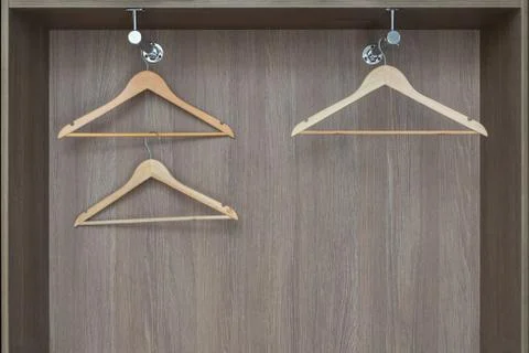 Fragment of modern wardrobe from inside. Empty wooden clothes hangers hang on Stock Photos