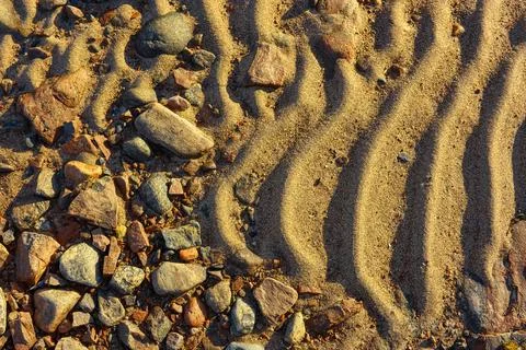 A fragment of a sandy beach with multi-colored stones Stock Photos