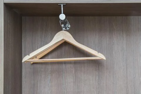 Fragment of wardrobe from inside. Empty light wooden clothes hangers hang fro Stock Photos